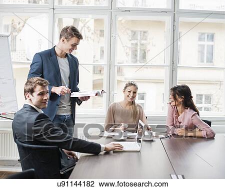 Young business people looking at laptop in meeting View Large Photo Image Stock Image - Young business people looking at laptop in meeting. Fotosearch