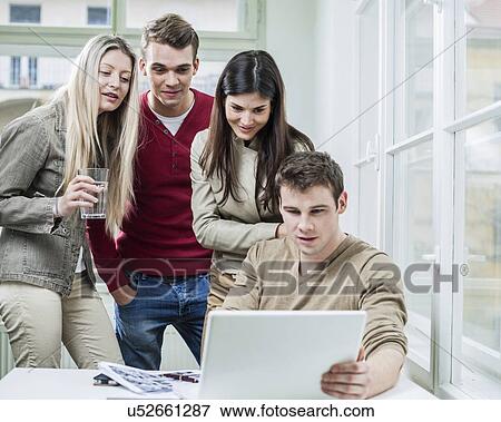 Stock Photo - Young business people looking at laptop in meeting. Fotosearch