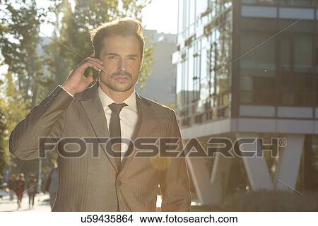 Young businessman conversing on cell phone outdoors View Large Photo Image Picture - Young businessman conversing on cell phone outdoors. Fotosearch