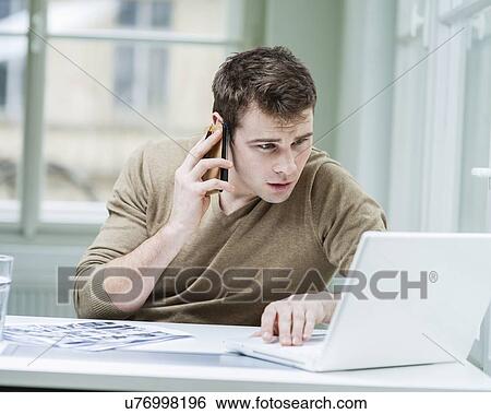 Young businessman using laptop while on call View Large Photo Image Stock Photograph - Young businessman using laptop while on call. Fotosearch