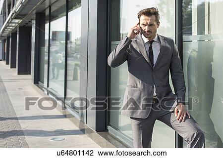 Young businessman using mobile phone outside office View Large Photo Image Stock Image - Young businessman using mobile phone outside office. Fotosearch