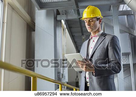 Young businessman using tablet computer in industry View Large Photo Image Picture - Young businessman using tablet computer in industry. Fotosearch