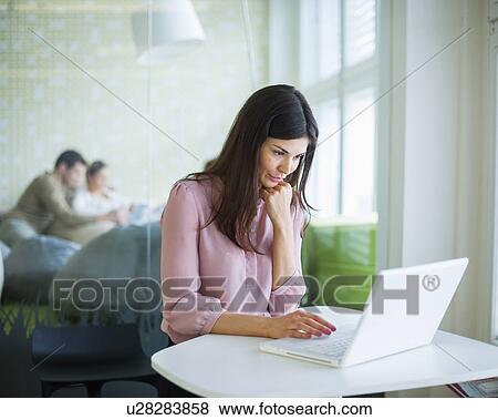 Stock Photo - Young businesswoman using laptop at office table. Fotosearch