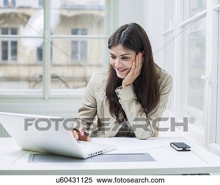 Young businesswoman using laptop at office desk View Large Photo Image Stock Photography - Young businesswoman using laptop at office desk. Fotosearch