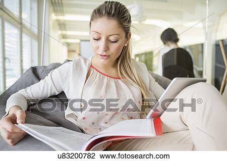Young businesswoman with digital tablet reading book in office View Large Photo Image Stock Image - Young businesswoman with digital tablet reading book in office. Fotosearch