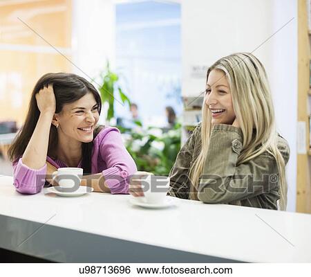 Young businesswomen smiling at cafeteria table View Large Photo Image Stock Photograph - Young businesswomen smiling at cafeteria table. Fotosearch