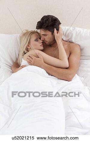 Stock Photography - Young couple cuddling in bed. Fotosearch