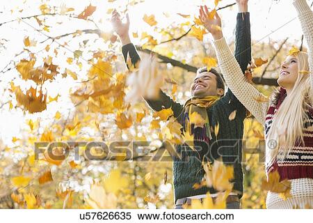 Young couple enjoying falling autumn leaves in park View Large Photo Image Stock Photography - Young couple enjoying falling autumn leaves in park. Fotosearch