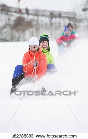 Stock Image - Young couple enjoying sled ride on snow covered slope. Fotosearch