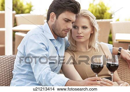 Picture - Young couple having red wine at outdoor restaurant. Fotosearch