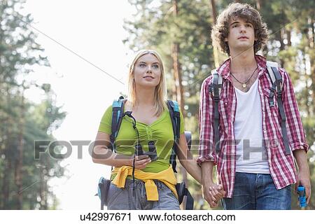Young couple looking away while hiking in forest View Large Photo Image Stock Image - Young couple looking away while hiking in forest. Fotosearch