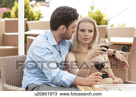 Young couple talking while having red wine at outdoor restaurant View Large Photo Image Stock Image - Young couple talking while having red wine at outdoor restaurant. Fotosearch
