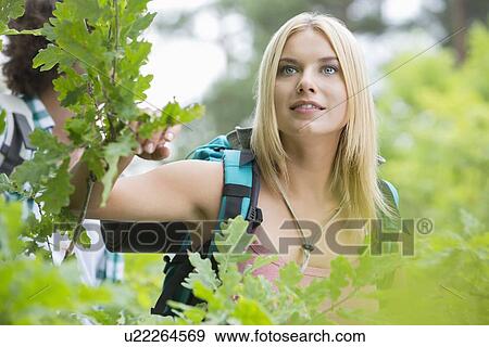 Stock Photo - Young female hiker in forest with man in background. Fotosearch