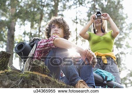 Young female hiker photographing through digital camera while man looking away in forest View Large Photo Image Stock Photography - Young female hiker photographing through digital camera while man looking away in forest. Fotosearch