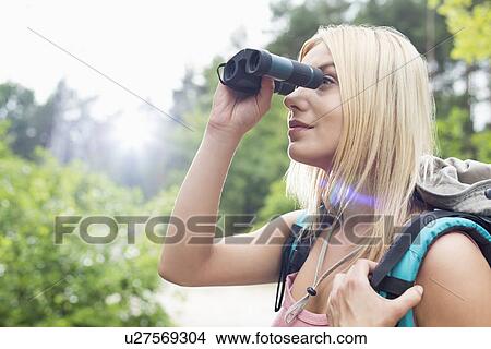 Young female hiker using binoculars in forest View Large Photo Image Picture - Young female hiker using binoculars in forest. Fotosearch