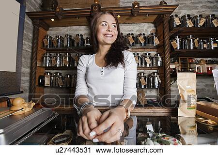 Stock Image - Young female owner looking away in tea store. Fotosearch