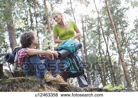 Stock Photo - Young hiking couple looking at each other in forest. Fotosearch