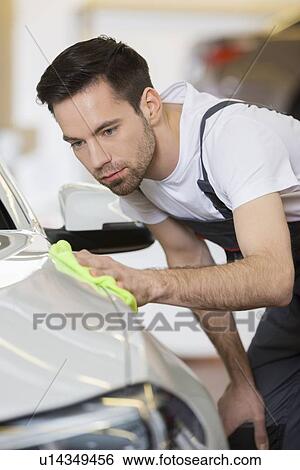 Stock Photograph - Young maintenance engineer cleaning car in repair shop. Fotosearch