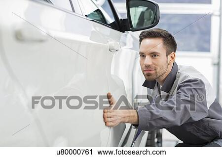 Young maintenance engineer examining car in repair shop View Large Photo Image Stock Image - Young maintenance engineer examining car in repair shop. Fotosearch