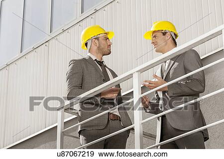 Young male architect discussing on stairway against building View Large Photo Image Stock Photo - Young male architect discussing on stairway against building. Fotosearch