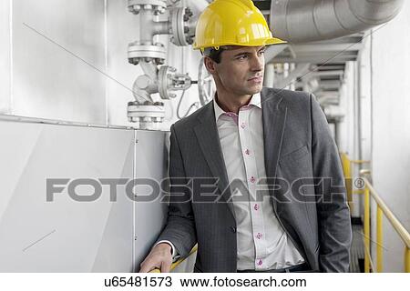 Young male architect in hard hat looking away at industry View Large Photo Image Stock Image - Young male architect in hard hat looking away at industry. Fotosearch