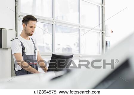 Young male automobile mechanic using computer in repair shop View Large Photo Image Stock Photography - Young male automobile mechanic using computer in repair shop. Fotosearch