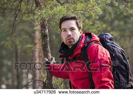 Stock Photograph - Young male backpacker in forest. Fotosearch