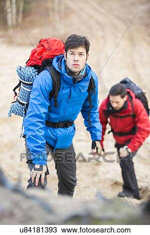 Young male backpackers hiking in forest View Large Photo Image Stock Image - Young male backpackers hiking in forest. Fotosearch