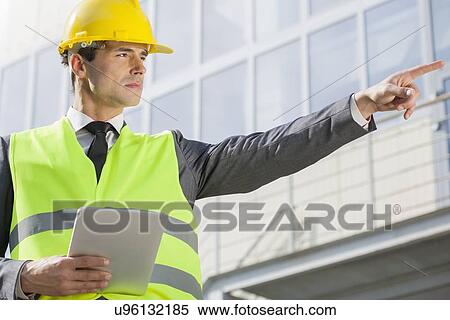Young male engineer with digital tablet pointing away outside industry View Large Photo Image Stock Photography - Young male engineer with digital tablet pointing away outside industry. Fotosearch
