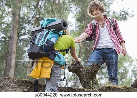 Young male hiker helping woman in climbing cliff at forest View Large Photo Image Stock Photo - Young male hiker helping woman in climbing cliff at forest. Fotosearch