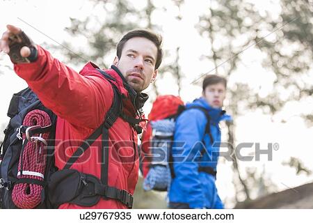 Young male hiker showing something to friend in forest View Large Photo Image Stock Photography - Young male hiker showing something to friend in forest. Fotosearch