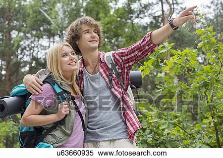 Stock Photography - Young male hiker showing something to woman in forest. Fotosearch