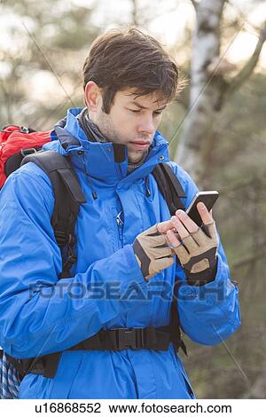 Young male hiker using smart phone in forest View Large Photo Image Stock Image - Young male hiker using smart phone in forest. Fotosearch