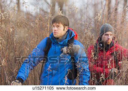 Young male hikers walking through field View Large Photo Image Stock Photography - Young male hikers walking through field. Fotosearch