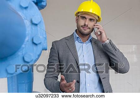 Young male manager using smart phone in industry View Large Photo Image Stock Image - Young male manager using smart phone in industry. Fotosearch