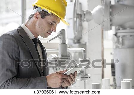 Stock Image - Young male supervisor using tablet PC in industry. Fotosearch
