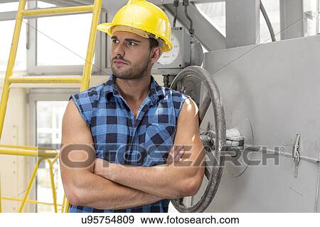 Young male worker standing arms crossed in industry View Large Photo Image Stock Photo - Young male worker standing arms crossed in industry. Fotosearch