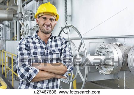 Stock Photograph - Young male worker standing arms crossed in industry. Fotosearch