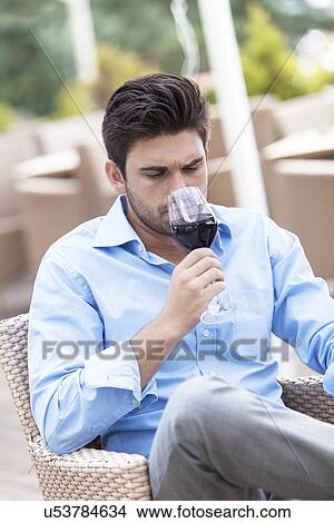 Picture - Young man drinking red wine at outdoor restaurant. Fotosearch