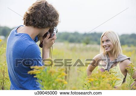 Young man photographing girlfriend in field View Large Photo Image Stock Image - Young man photographing girlfriend in field. Fotosearch