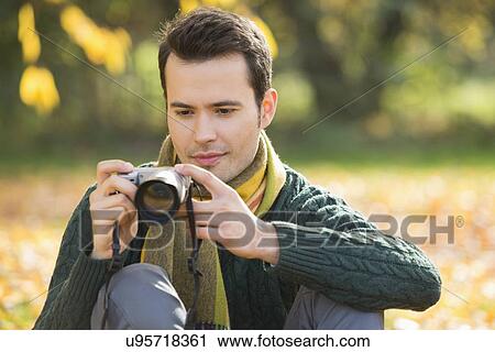 Young man photographing in park during autumn View Large Photo Image Stock Image - Young man photographing in park during autumn. Fotosearch