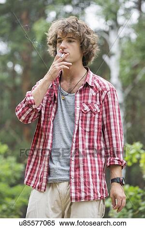 Stock Photography - Young man smoking in forest. Fotosearch