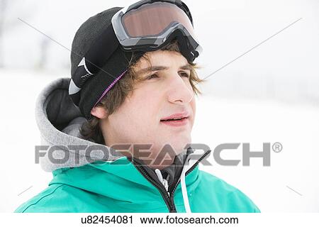 Stock Image - Young man wearing ski goggles outdoors. Fotosearch