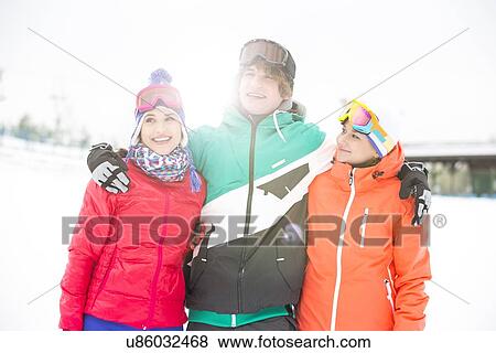 Young man with female friends standing arm around in snow View Large Photo Image Stock Photo - Young man with female friends standing arm around in snow. Fotosearch