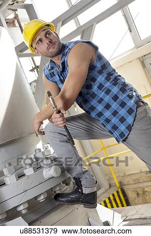 Young manual worker holding wrench in industry View Large Photo Image Stock Photo - Young manual worker holding wrench in industry. Fotosearch