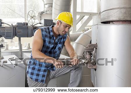 Young manual worker using wrench on industrial machine View Large Photo Image Stock Photo - Young manual worker using wrench on industrial machine. Fotosearch