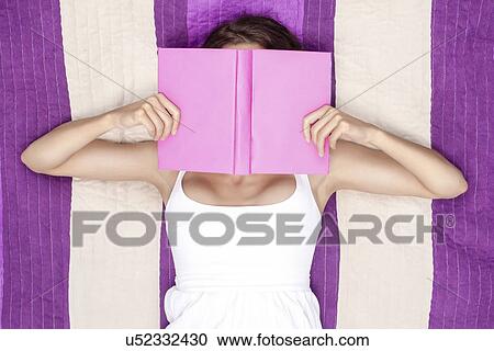 Young woman covering face with book while lying on picnic blanket View Large Photo Image Stock Image - Young woman covering face with book while lying on picnic blanket. Fotosearch