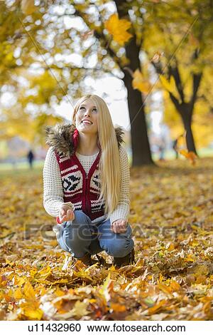 Young woman crouching while looking up in park during autumn View Large Photo Image Stock Image - Young woman crouching while looking up in park during autumn. Fotosearch