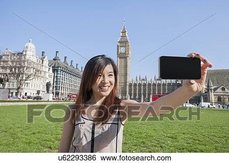 Young woman taking self portrait through smart phone against Big Ben at London, England, UK View Large Photo Image Stock Photograph - Young woman taking self portrait through smart phone against Big Ben at London, England, UK. Fotosearch