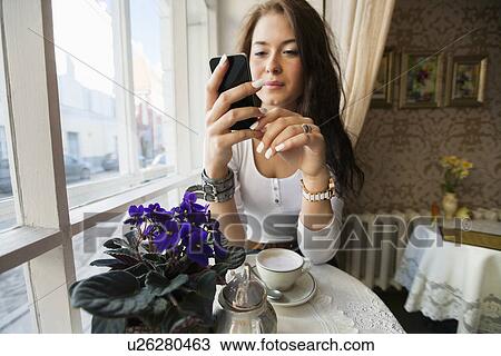 Young woman using smart phone at cafe table View Large Photo Image Stock Image - Young woman using smart phone at cafe table. Fotosearch